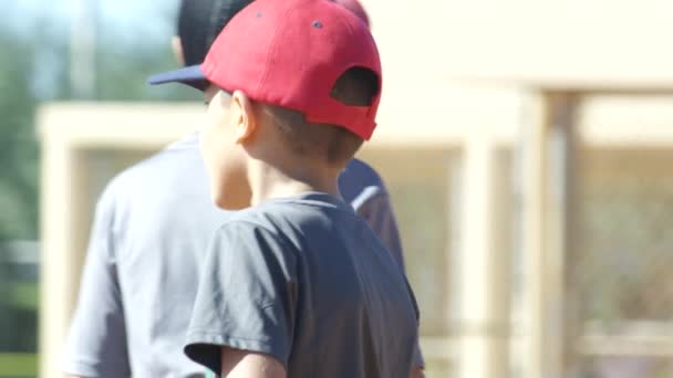 Медленное движение сзади мальчика ходьба и стоять во время бейсбольной тренировки — стоковое видео