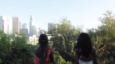 Ağır çekim shot iki Afrikalı-Amerikalı kadın Downtown Los Angeles doğru güzel bir günde arıyorsunuz bir Park'ta yürüyüş