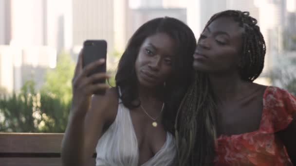 慢动作拍摄的两个非洲裔美国妇女微笑着和采取自拍的背景下洛杉矶市中心 — 图库视频影像
