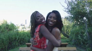 Güzel yavaş çekim sarılma ve arka planda Downtown Los Angeles ile kameraya gülümseyen iki Afrikalı-Amerikalı kadın