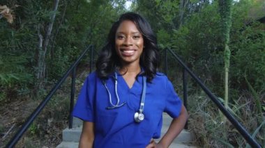 Önlük giyen ve kameraya bakarak ve gülümseyen, dışarı içinde belgili tanımlık açık havada Afrika kökenli Amerikalı kadının ağır çekim