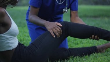 Bükme ve bir park başka bir kadının bacak Germe bir Afrikalı-Amerikalı ağır çekim yakın çekim çekim hemşire