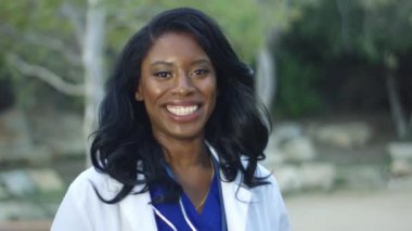 Ağır çekim, Afrikalı-Amerikalı kadın doktor beyaz ceket kameraya gülümseyen