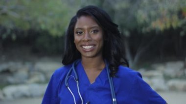 Afrikalı-Amerikalı ağır çekim güzel hemşire scrubs kameraya gülümseyen içinde