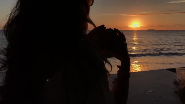 Γυναίκα Απολαμβάνοντας Ηλιοβασίλεμα Μπροστά Μια Παραλία Και Πόσιμο Νερό Καρύδας — Αρχείο Βίντεο