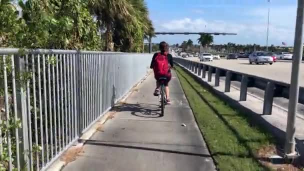 Mujer Con Una Mochila Montando Una Bicicleta Sendero Junto Carretera — Vídeo de stock