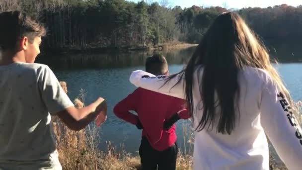 美丽的慢动作拍摄的孩子接近另一个孩子谁站在湖前 拥抱他 — 图库视频影像