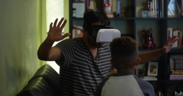父亲和儿子的慢动作玩虚拟现实耳机 而坐在家里 — 图库视频影像