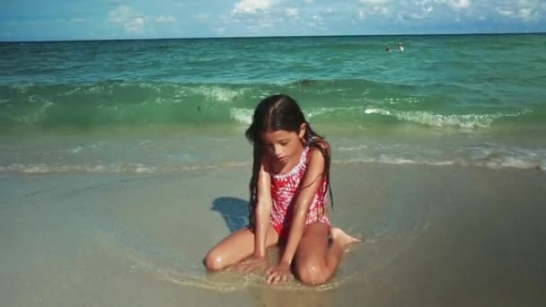 伟大的拍摄一个美丽的小女孩坐在前面的海洋玩水和沙子 — 图库视频影像