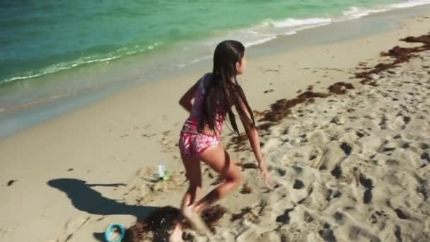 拍摄的女孩微笑着在相机 运行和做一个车轮在美丽的一天在海滩上的海洋 — 图库视频影像