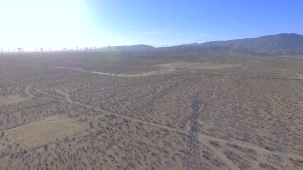 カリフォルニアの野原の上空を撮影し 下に移動して電気塔と風車を背景に表示 — ストック動画