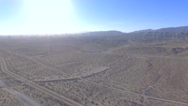 カリフォルニアの野原の上空を撮影した昼間の空中写真は 背景の風車のグループから移動します — ストック動画
