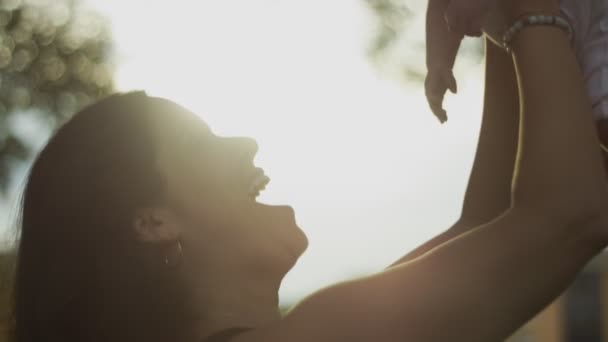 Madre che tiene il bambino e sorride durante il tramonto — Video Stock