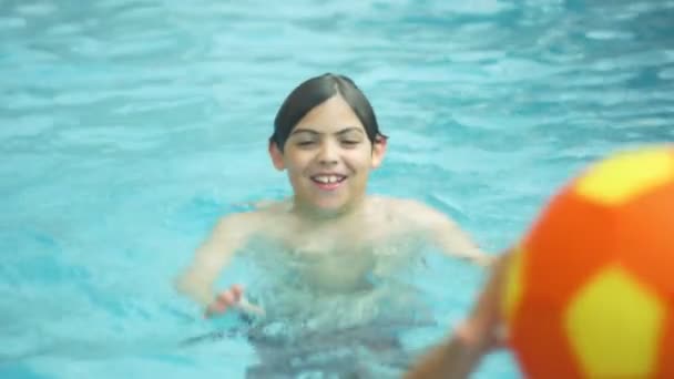 Slow Motion av ett barn leker med en boll inuti en swimmingpool — Stockvideo