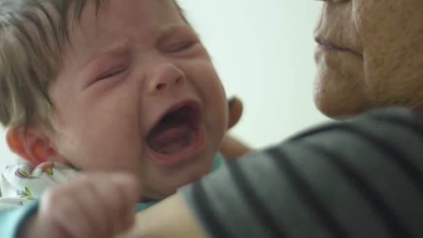 Κοντινό-up σε αργή κίνηση της γιαγιάς κρατώντας κλάμα μωρό — Αρχείο Βίντεο