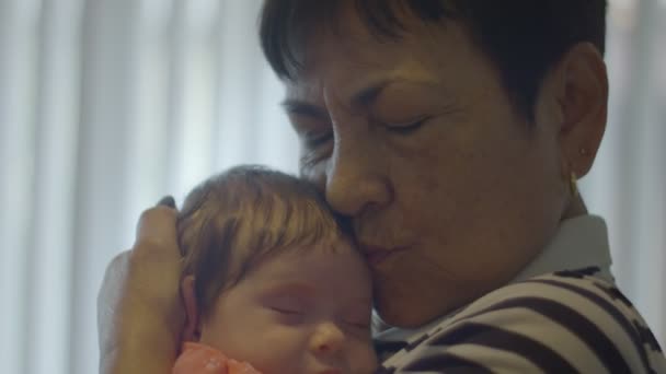 Mouvement lent d'une grand-mère tenant et embrassant bébé — Video