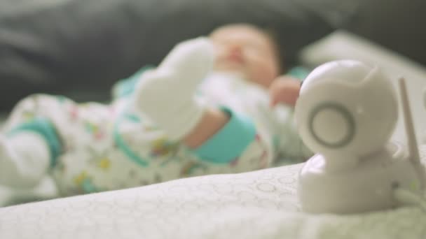 Movimento lento do bebê se movendo na cama ao lado do monitor do bebê — Vídeo de Stock