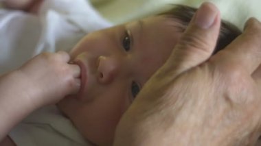 Parmak emen bebeğin başını okşayan elin yavaş hareketi