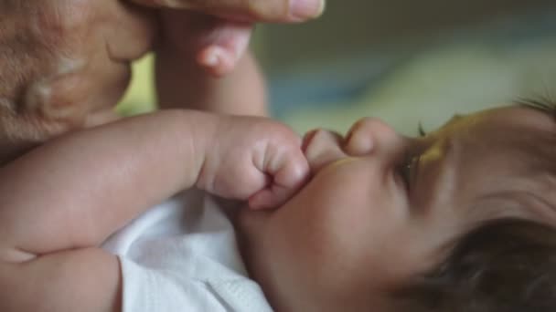 Slow Motion van de baby met de hand in de mond en het houden van grootvaders vinger — Stockvideo