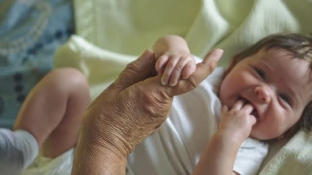 Mooie Slow Motion van baby glimlachen en houden grootvaders vinger — Stockvideo