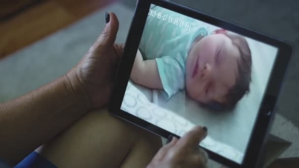 Cámara lenta de la abuela revisando el bebé a través de la tableta — Vídeos de Stock