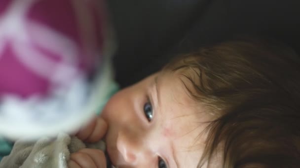 Close-up em câmera lenta de bebê segurando cobertor e olhando para móvel em movimento — Vídeo de Stock