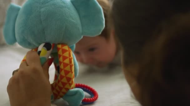 Slow motion of woman holding toy in front of baby during belly time — Stock Video