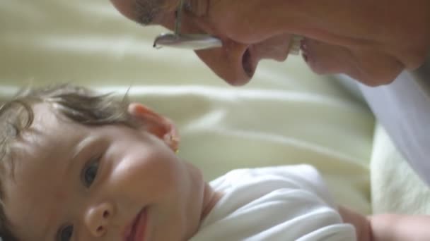 Медленное движение ребенка, улыбающегося в камеру, когда дедушка разговаривает с ней — стоковое видео