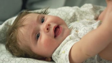 Güzel bebeğin yavaş hareketi uzanıp ayaklarla oynuyor