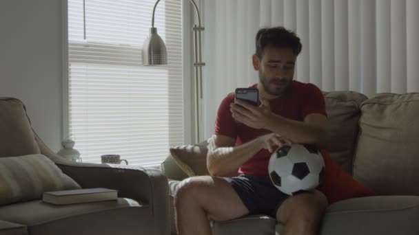 Slow Motion van voetbal fan zoenen een voetbal bal en het houden van mobiele telefoon — Stockvideo