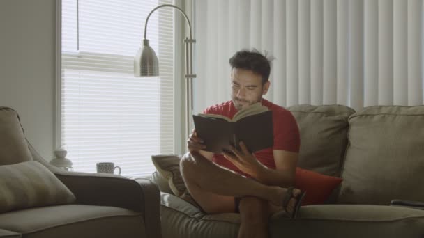 Zeitlupe eines Mannes, der zu Hause ein Buch schließt und darüber nachdenkt — Stockvideo