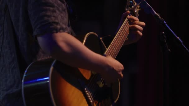 Медленное движение музыканта, играющего на акустической гитаре на сцене — стоковое видео
