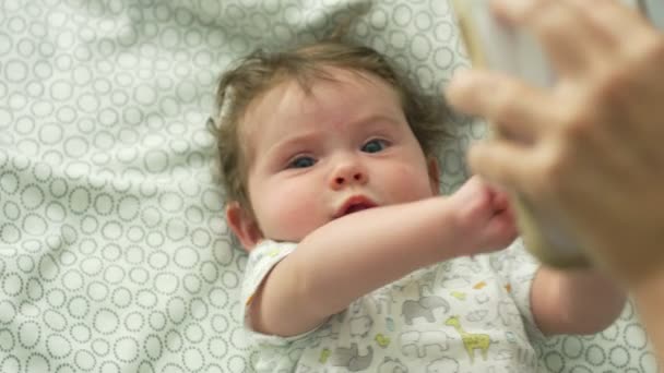 Повільний рух дитини, дивлячись на мобільний телефон, лежачи в ліжку — стокове відео