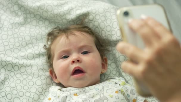 Lassú mozgás a baba tüssző, miközben felnézett a mobiltelefonján — Stock videók
