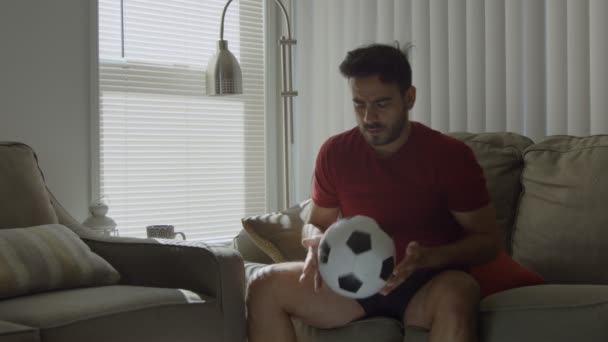 Cámara lenta del hombre jugando con la pelota de fútbol en casa se levanta y se va — Vídeo de stock