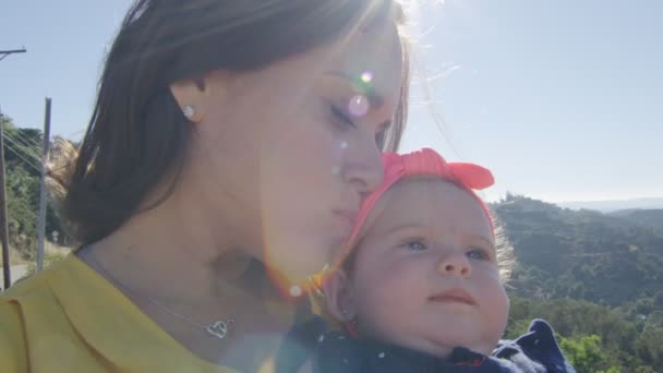 Slow Motion van moeder zoenen haar baby dochter in de voorkant van de bergen — Stockvideo