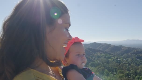 Movimento lento da mãe e da filha bebê na frente da bela vista — Vídeo de Stock