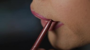 Cinsiyet değiştiren kadın dudak kalemiyle ruj sürüyor.
