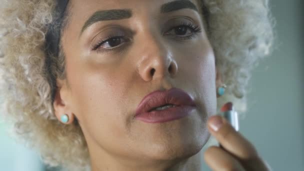 Трансгендерна жінка одягає губну помаду з сумним виразом. — стокове відео