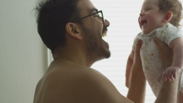 Slow Motion van man het opheffen van zijn baby dochter thuis — Stockvideo