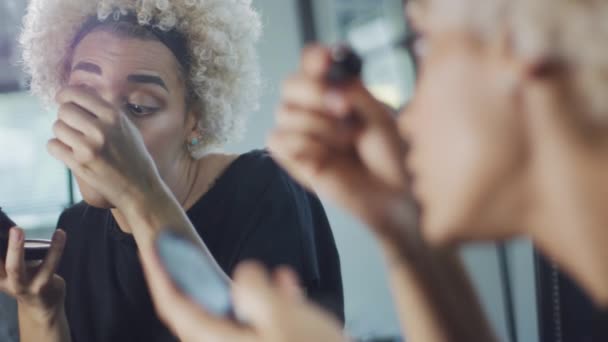 Transgender woman putting mascara on in front of a mirror — ストック動画