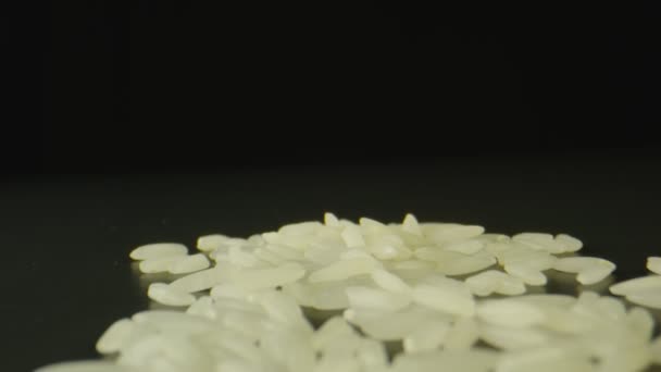 Macro shot of grains of rice on top of black table, black background — Stock Video