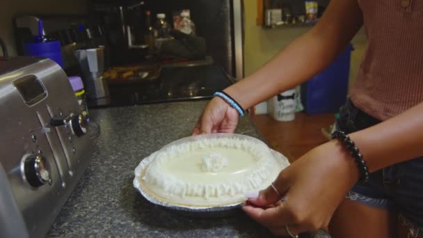Повільний рух дівчини, що покриває пиріг пластиковою кришкою — стокове відео
