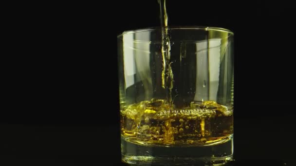 Makro-Nahaufnahme von Alkohol, der auf ein Glas gegossen wird. Hintergrund ist schwarz. — Stockvideo