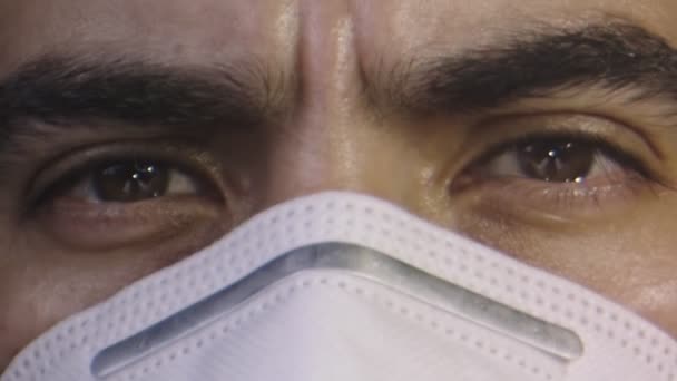 Close-up de cara de homem com uma máscara facial, olhos castanhos, olhada séria — Vídeo de Stock