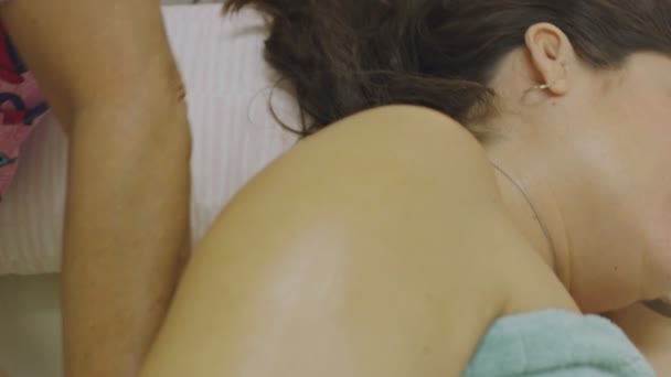 Повільний рух масажистки, що дає вагітній жінці масаж спини — стокове відео