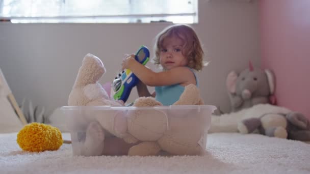 Little girl playing inside bin in her room with toy guitar — Stock Video