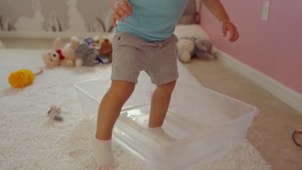 Little girl getting inside a plastic bin in her room and sitting to play — Stock Video