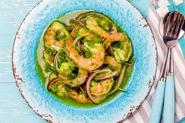 Meksika mutfağı. Aguachile de camaron. Karides aguachile. Karides eviche cebiche salatalık ile limon ve mor soğan. Üstten görünüm, mavi arka plan.