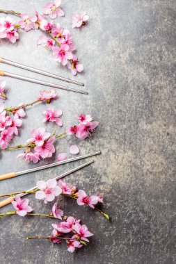 Yemek çubukları ve sakura dalları gri taş zemin üzerine. Japon gıda kavramı. Üstten görünüm, kopya alanı
